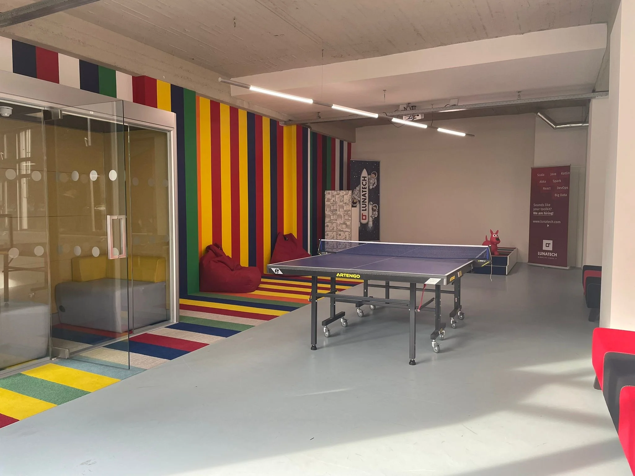 Kleurrijke ontspanningsruimte met een pingpongtafel, zitzakken en glazen vergaderruimte bij Lunatech aan de Van Leijenberghlaan.